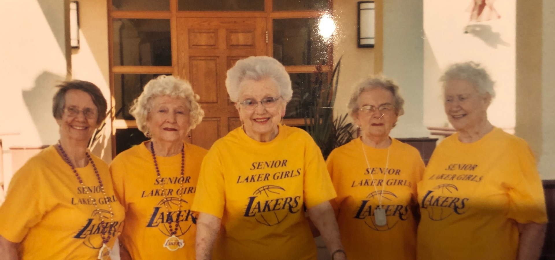 A joyful group of senior women smiling together in matching yellow Senior Laker Girls shirts